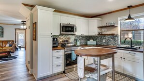 A modern kitchen with white cabinetry, a central island, a microwave, and a coffee maker. - Pet-friendly Granbury Home w/ Yard, Near Downtown! (Granbury)