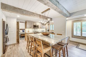 Une cuisine spacieuse avec un grand îlot central, des tabourets de bar en bois et un plafond rustique.