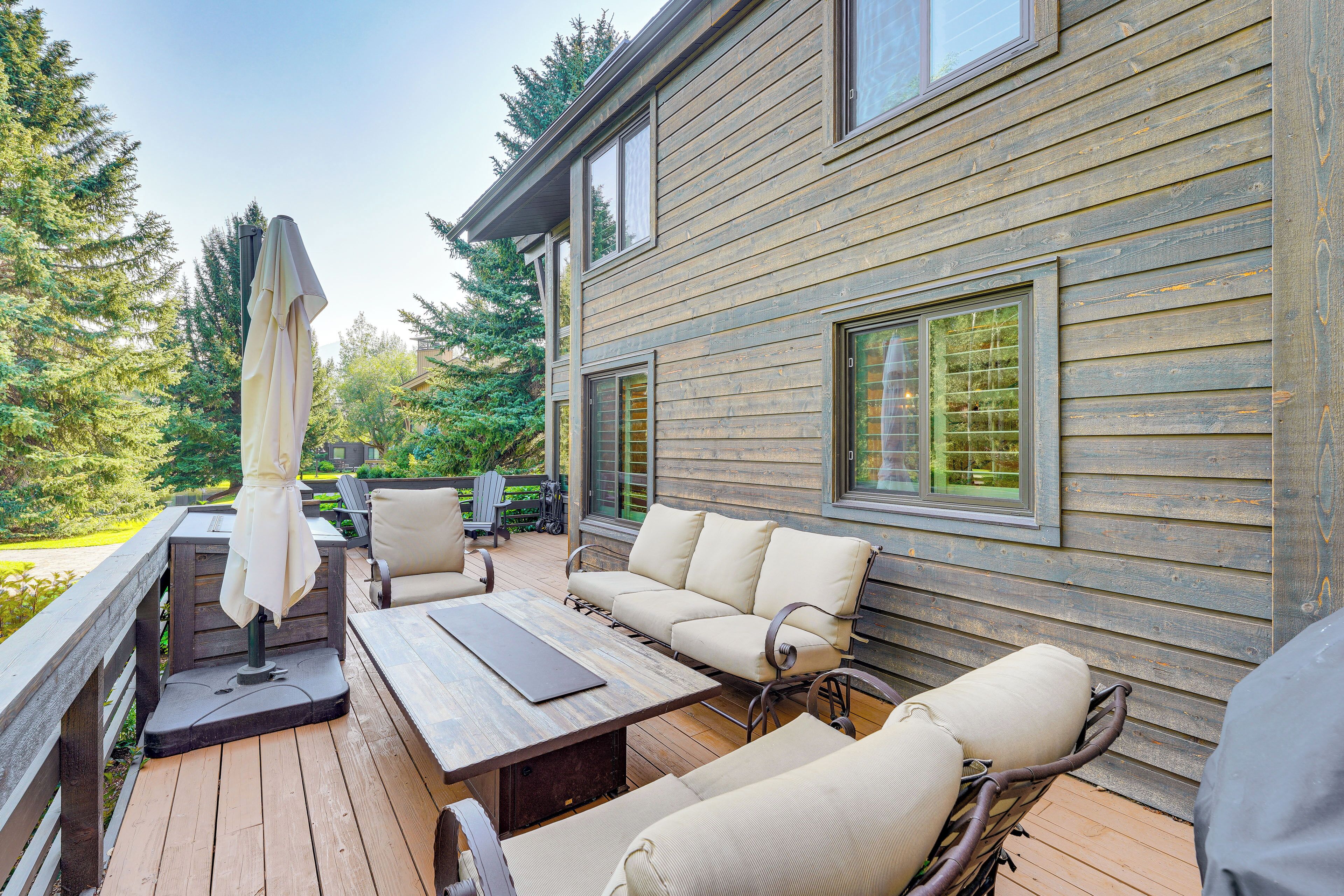 Une terrasse en bois aménagée avec du mobilier d’extérieur, notamment un canapé et des fauteuils, ainsi qu’une table.