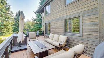 Une terrasse en bois aménagée avec du mobilier d’extérieur, notamment un canapé et des fauteuils, ainsi qu’une table.