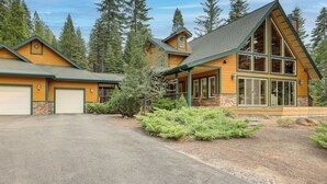 A two-story log cabin with a large front porch, stone foundation, and a garage. - Cozy Chester Home w/ Patio & Lake Access! (Chester)