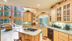 A spacious kitchen with wooden cabinets, a granite countertop, and a large island with stools. - Cozy Chester Home w/ Patio & Lake Access! (Chester)