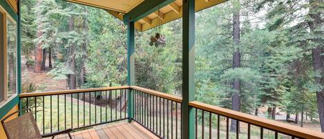 A wooden deck with a railing, a chair, and a hanging ornament.