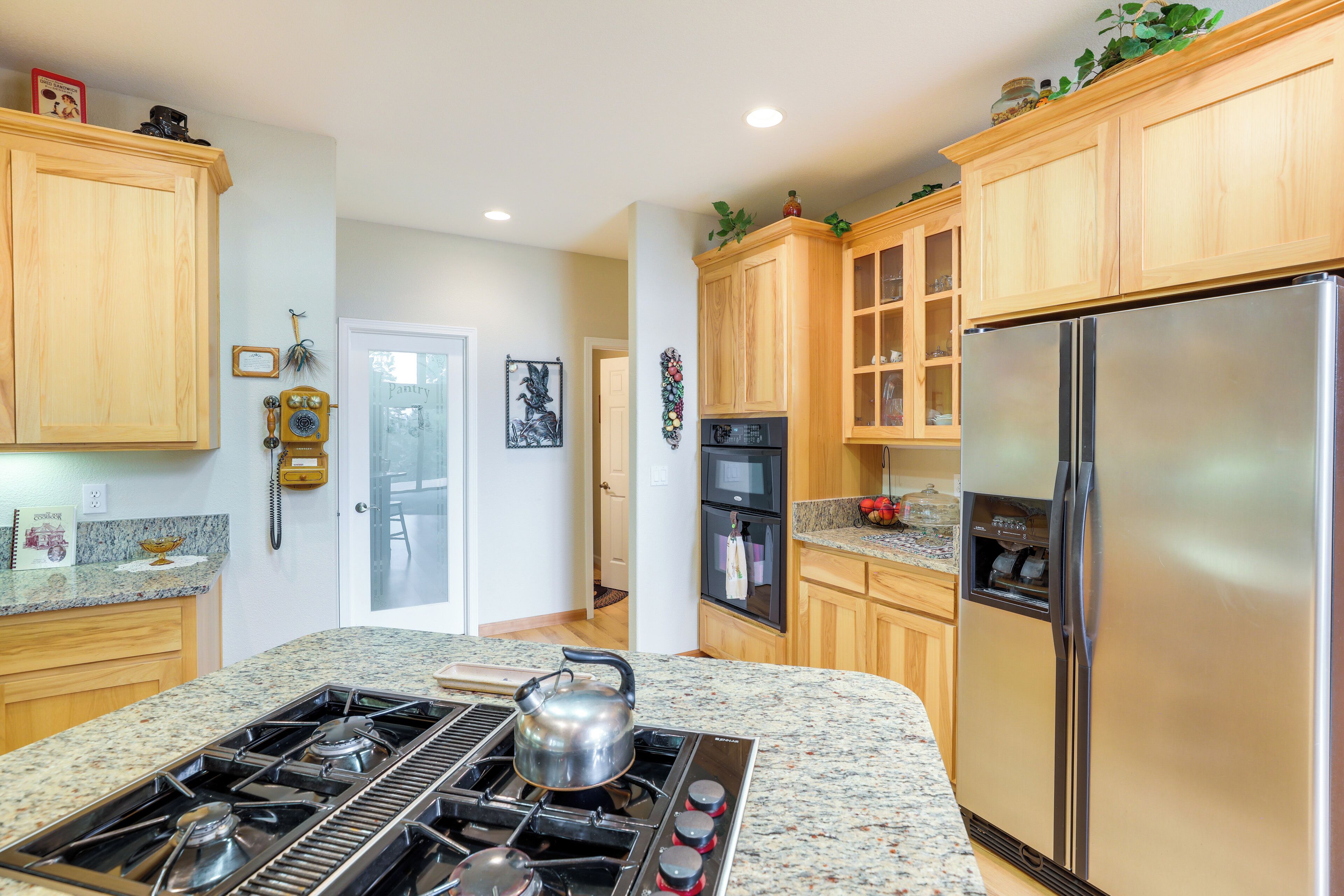 A kitchen with granite countertops, wooden cabinets, a stainless steel refrigerator, and a gas stove.