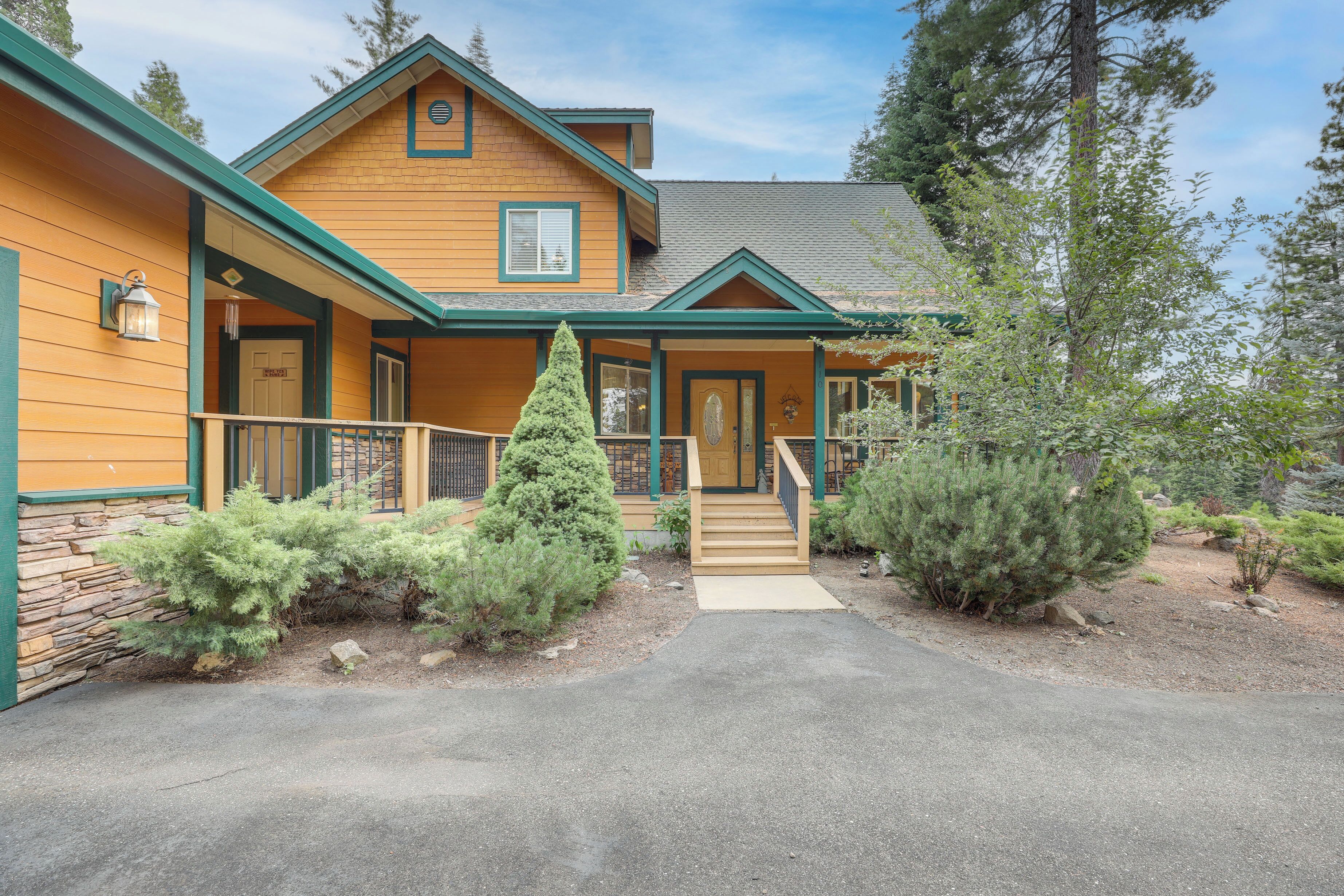 A two-story wooden house with a front porch, a stone foundation, and a well-maintained garden.