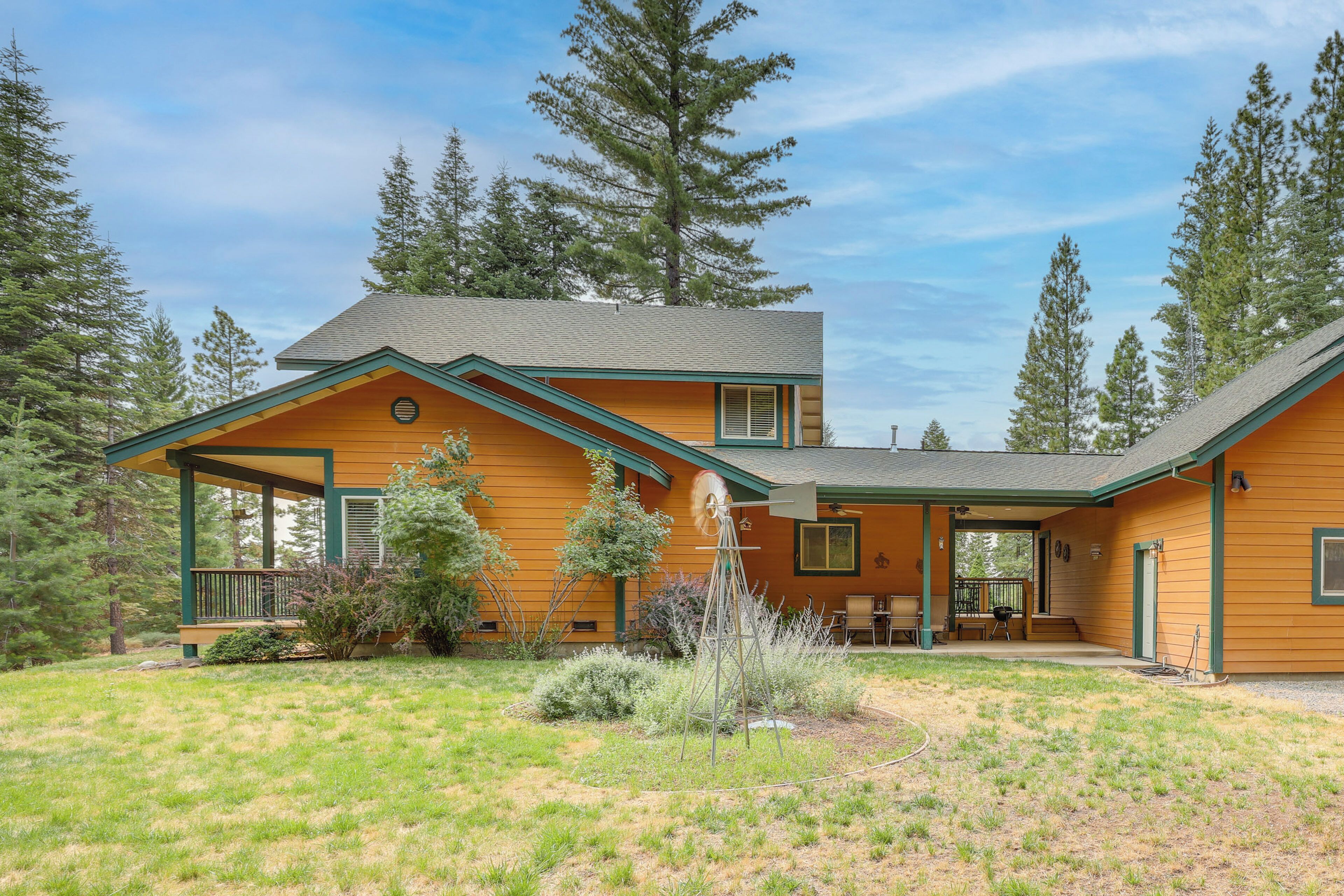 A two-story log cabin with a covered porch and a small outdoor seating area.