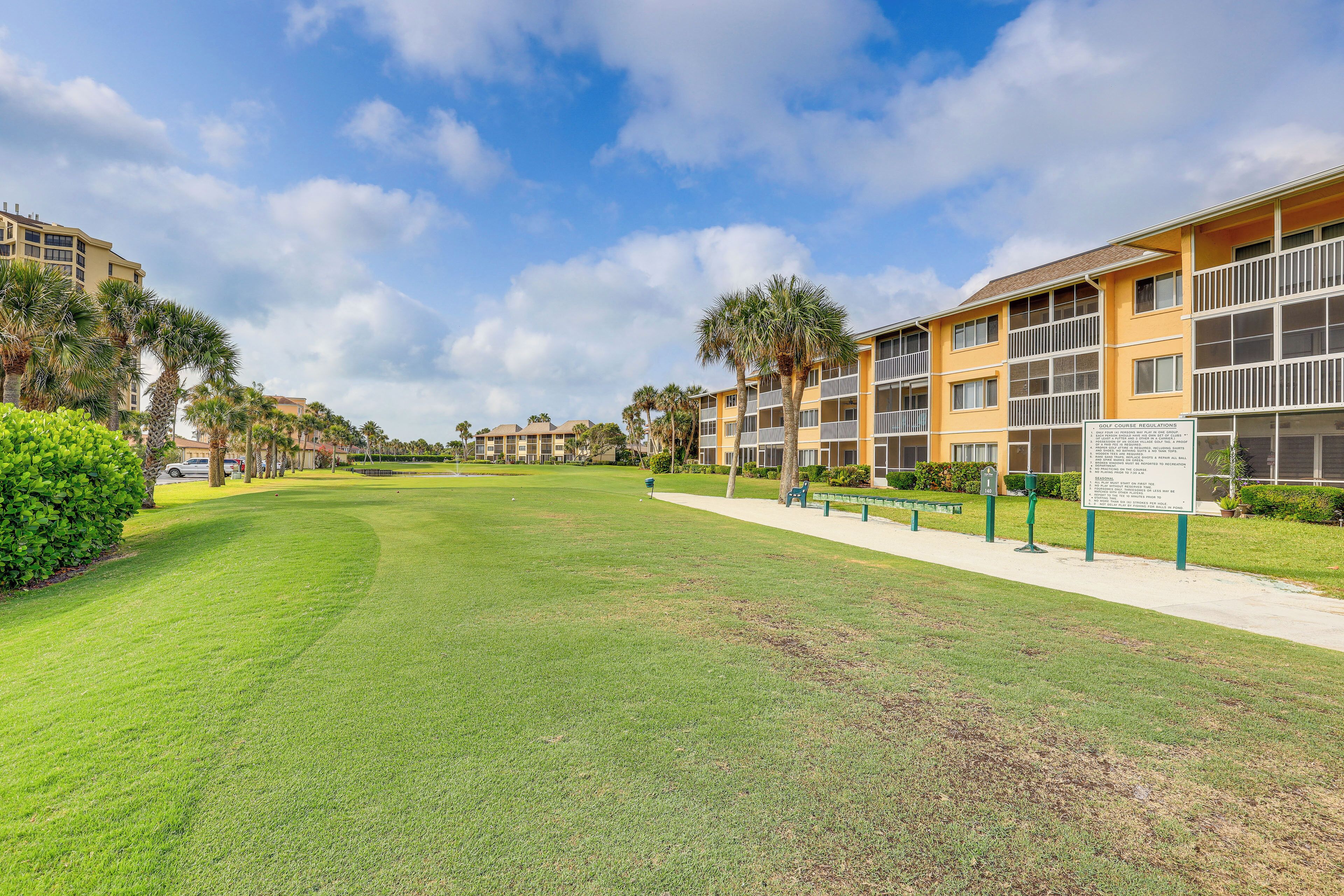 A well-maintained grassy area with a pathway leading to a multi-story building with balconies.