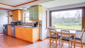 A kitchen with wooden cabinets, a stove, and a dishwasher. There is a window with a view of trees and a grassy area. - Pet-friendly New Berlin Retreat w/ Patio & Yard! (New Berlin)