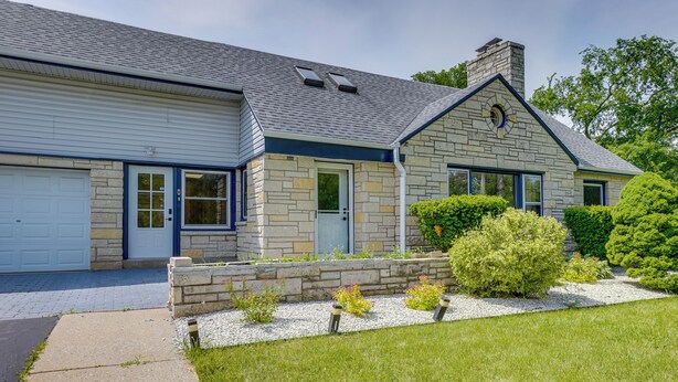 A two-story house with a stone facade, a garage, and a well-maintained lawn. - Pet-friendly New Berlin Retreat w/ Patio & Yard! (New Berlin)