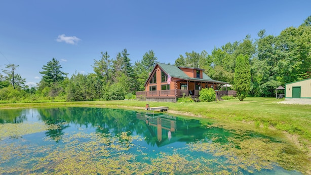 Un chalet doté d’un grand étang, entouré d’une végétation luxuriante et d’arbres.