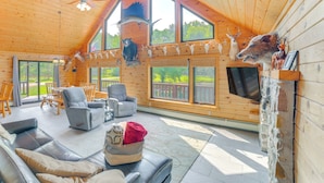 L’intérieur d’une cabane en rondins, avec une cheminée, des têtes d’animaux empaillées accrochées au mur et un téléviseur.