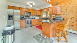 Une cuisine moderne avec des meubles en bois, des appareils électroménagers en acier inoxydable et un îlot central en bois doté de tabourets de bar.