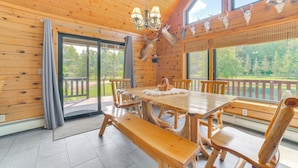 Un intérieur en bois avec une grande table à manger, des bancs et un lustre.