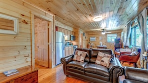 A cozy cabin interior with a wooden interior, a leather sofa, a dining table, and a kitchen area. - Bryson City Cabin in Smoky Mtn w/ Resort Amenities (Bryson City)