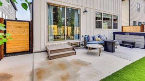 Eine Terrassenanlage mit einer Sitzecke, einem Tisch und einem Whirlpool.