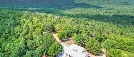 Una casa rodeada de bosque denso y con una vista despejada del paisaje circundante.