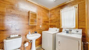 A bathroom with wooden walls, a sink, a toilet, and a washing machine.