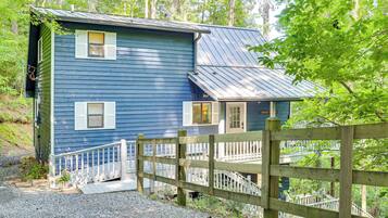 A two-story blue house with a wooden deck and a staircase leading to the second floor.
