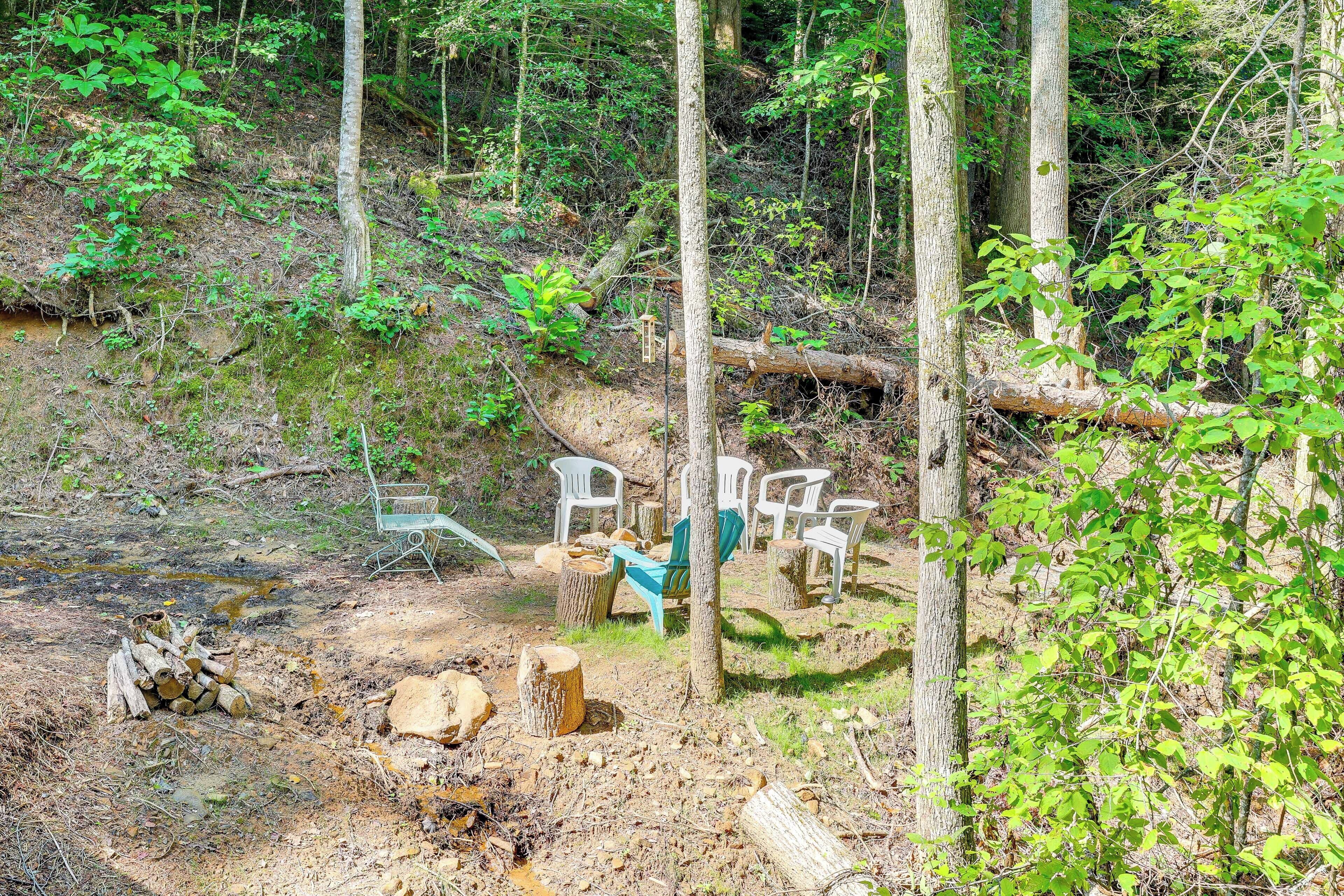 A rustic outdoor setting with a dirt ground, scattered logs, and a pile of firewood.