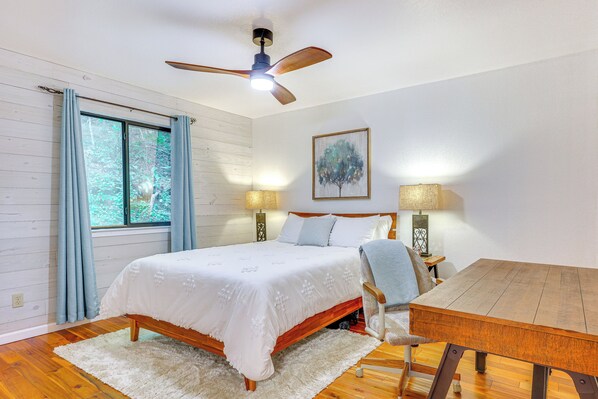 A bedroom with a bed, a wooden table, a ceiling fan, and a window with curtains. - Lakefront Murphy Getaway w/ Deck, Dock & Kayaks! (Murphy)