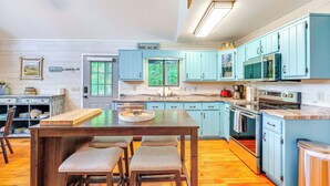 A kitchen with light blue cabinets, a wooden table with four chairs, a sink, and a view of the outdoors through a window. - Lakefront Murphy Getaway w/ Deck, Dock & Kayaks! (Murphy)