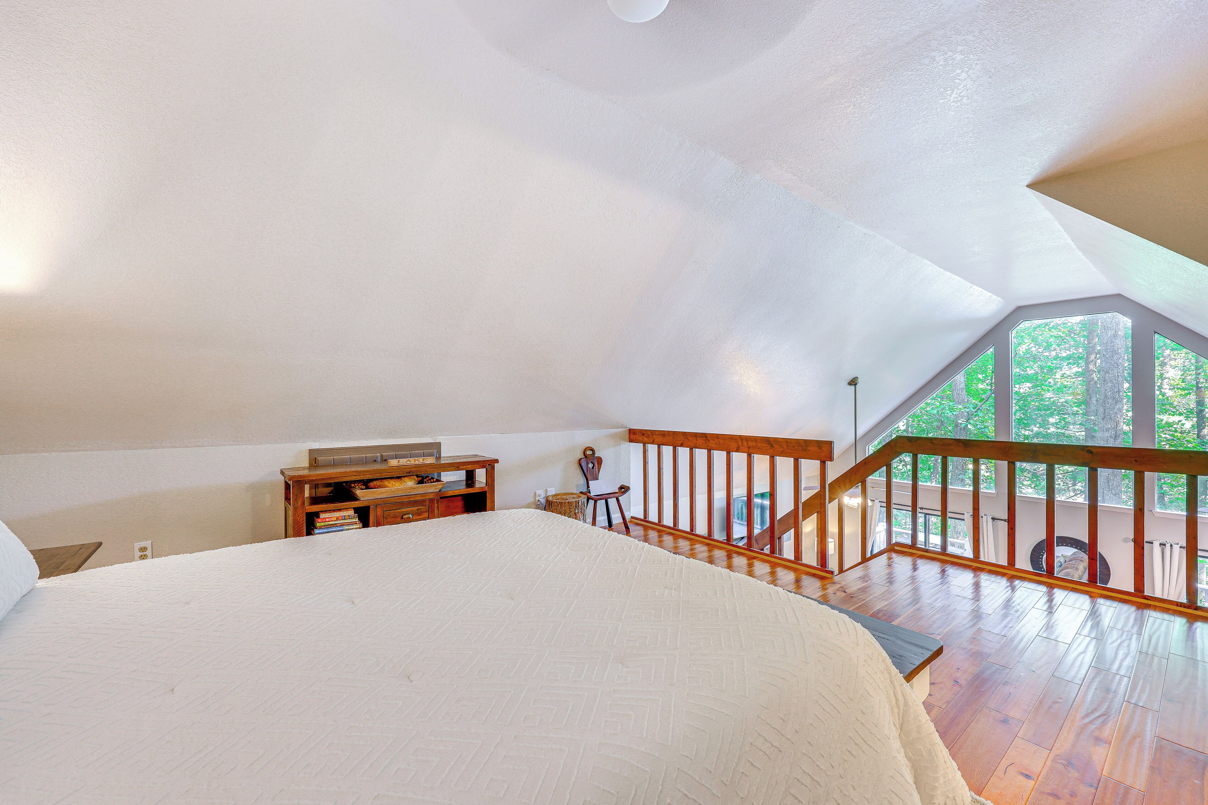 A bedroom with a large bed, wooden furniture, and a view of trees through a window.