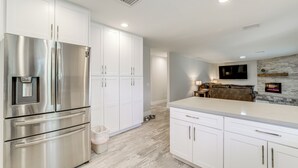 A modern kitchen with stainless steel appliances, white cabinetry, and a stone accent wall.