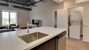 A modern kitchen with a large island, built-in dishwasher, and a flat-screen TV.