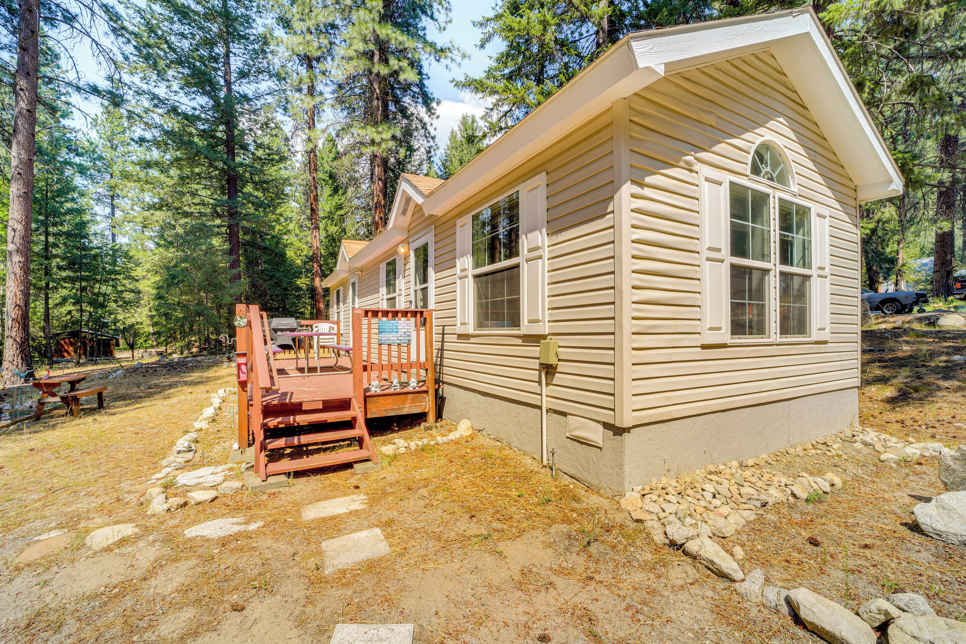 A small cabin with a porch, surrounded by trees.