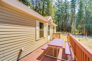 A wooden deck with picnic tables and a railing, surrounded by a forested area. - Peaceful Entiat Home: Pets Welcome! (Entiat)