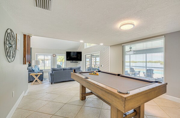 A pool table in a living room with a sofa and TV in the background.