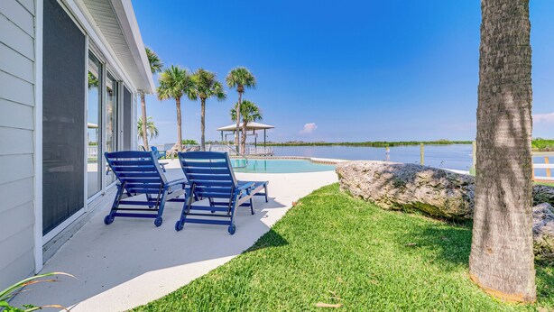 A pool area with lounge chairs, a gazebo, and palm trees. - Boat Dock & Pool: Bayfront Crystal River Home (Crystal River)