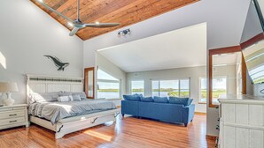 A spacious bedroom with a large bed, a blue sofa, and a wooden ceiling. - Boat Dock & Pool: Bayfront Crystal River Home (Crystal River)