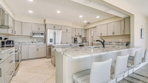 A modern kitchen with a central island, built-in appliances, and bar seating. - Boat Dock & Pool: Bayfront Crystal River Home (Crystal River)