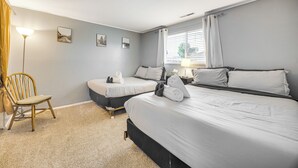 Ein Hotelzimmer mit zwei Betten, einem Sessel und einer Lampe.
