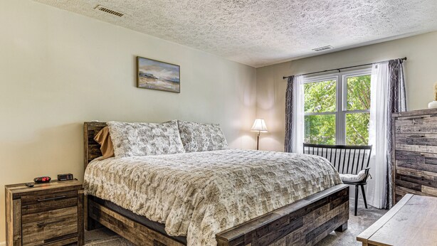 A bedroom with a wooden bed, a nightstand, a chair, and a window with curtains. - 14 Mi to Lucas Oil Stadium: Fire Pit & Grill! (Indianapolis)