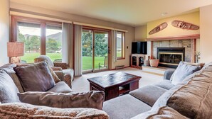 Amplia sala de estar con chimenea, ventanas grandes y vistas al exterior.