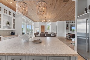 A spacious kitchen with a large island, wooden ceiling, and modern appliances.