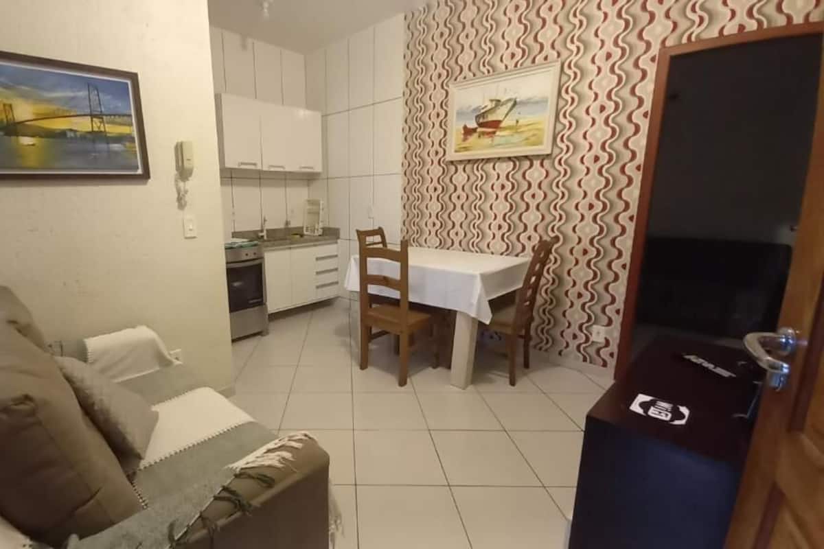 Een knus woongedeelte met een kitchenette, een eethoek en een bank.