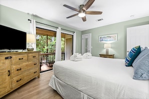 A bedroom with a bed, a TV, a ceiling fan, a nightstand, and a view of the outdoors. - 2Br/2.5Ba, 2 Pools, Tennis, Beach Access! + Free Attraction Tickets! (Santa Rosa Beach)