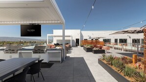 Une terrasse extérieure moderne, dotée d’un écran de télévision, de sièges et offrant une vue sur la ville.