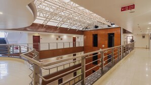 Interior de varios niveles con una escalera central, barandillas de metal y un letrero de salida de incendios.