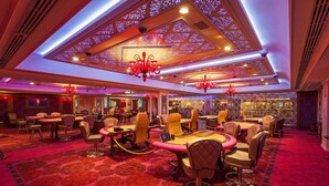 Una habitación amplia con techo alto, diseño ornamental en el techo, varios candelabros y suelo cubierto de alfombra roja.