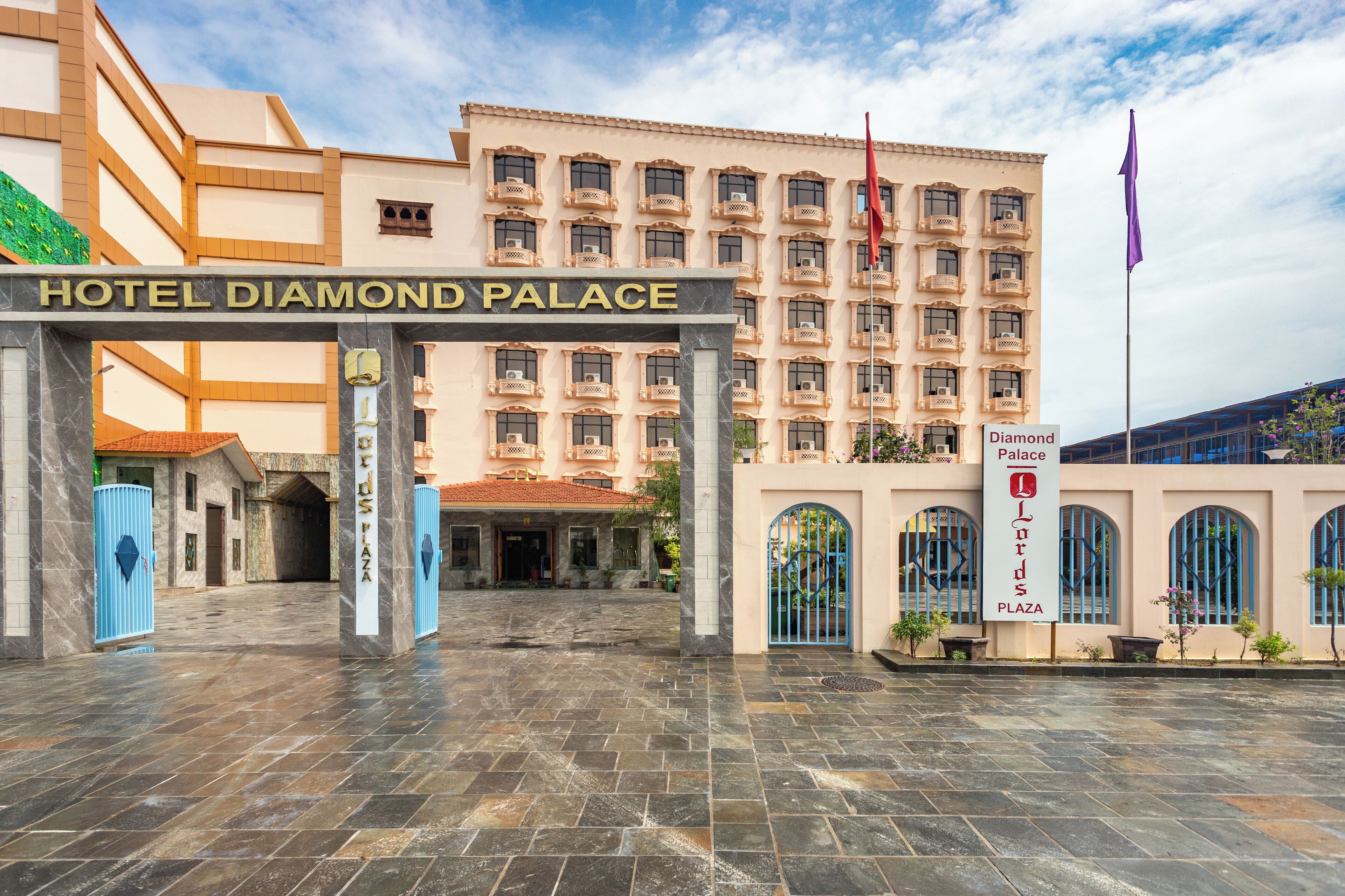 The entrance to Hotel Diamond Palace with a stone-paved courtyard and a large building with multiple balconies.