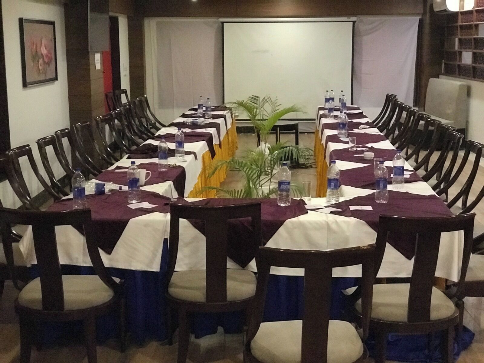 A conference room with a long table, chairs, and a projector screen.