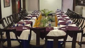 A conference room with a long table, chairs, and a projector screen.