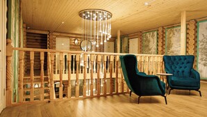 A wooden interior with a balcony, two chairs, and a hanging light fixture. - Skala (Burabay)
