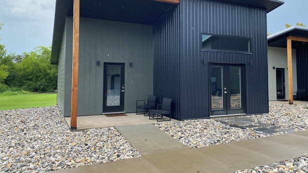 A modern building with a large open patio area, a covered seating area, and a gravel pathway. - Lovely 2-bedroom cottage located in downtown Mount Vernon! (Mount Vernon)