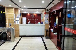 A hotel reception area with a reception desk, a scale, and a glass door leading to a lobby. - Shenghao Hotel (Guangzhou Railway Station) (Guangzhou)