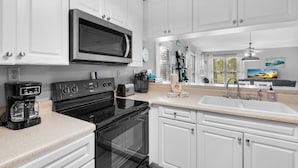 A modern kitchen with white cabinets, a built-in microwave, a stove, and a sink. - 🌊Beachview 107-🐾Pet Friendly🐾-2BR-Close To The Beach🌊 (Navarre Beach)